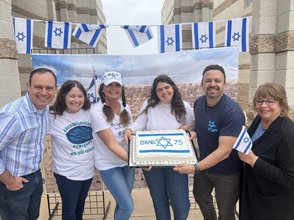 CBI team members celebrate Israel and hold a cake decorated as the Israeli flag.