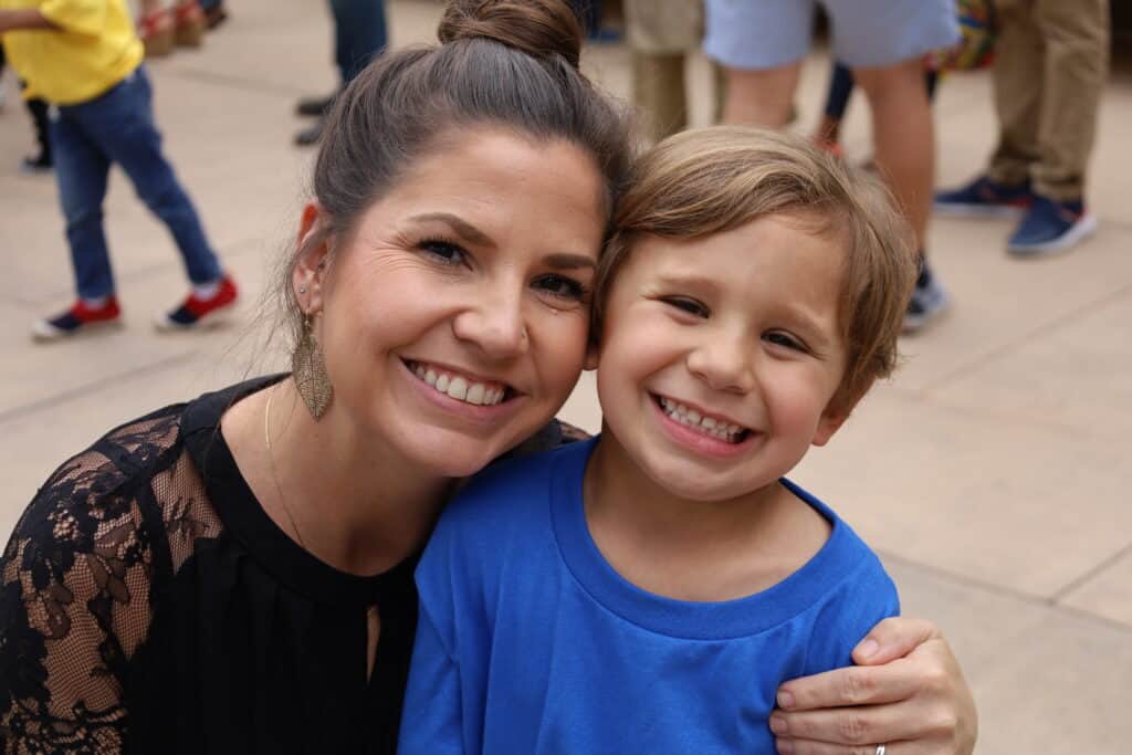 A mother and preschool student smile together.