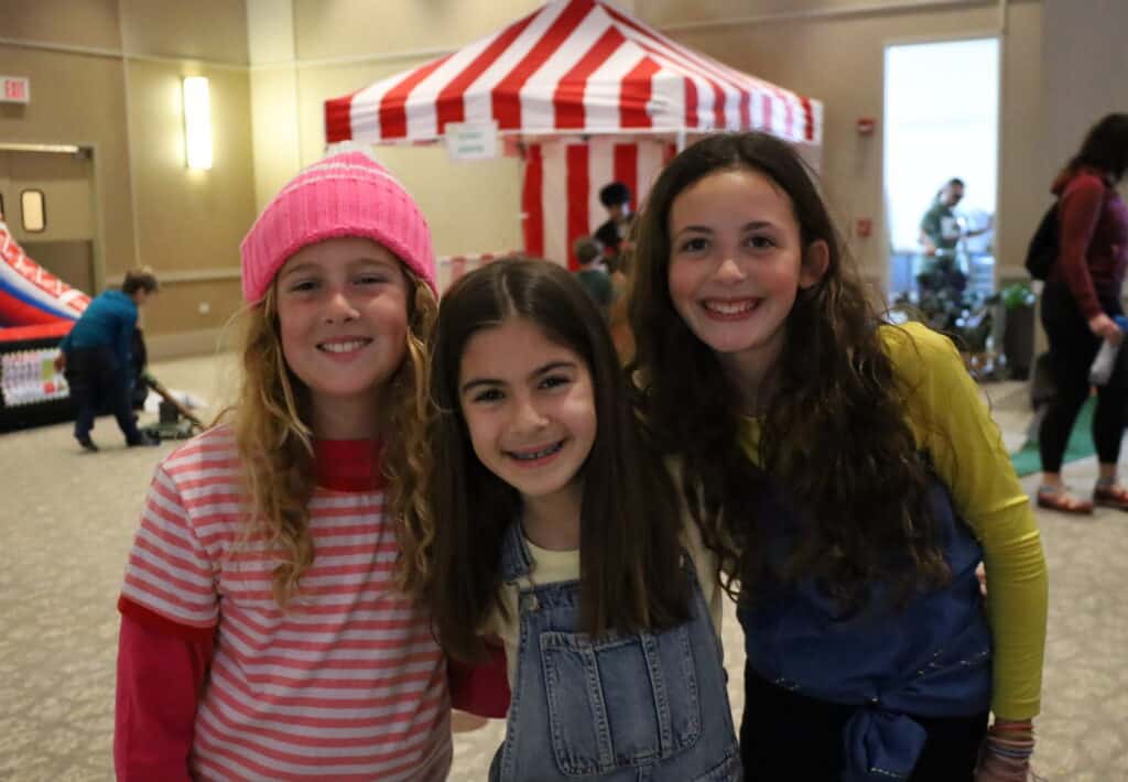 Three young girls pose during the CBI Purim carnival.