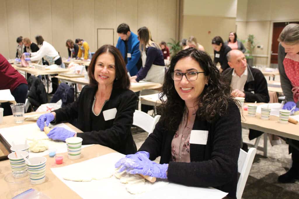 Two women baking challah at a Congregation Beth Israel event