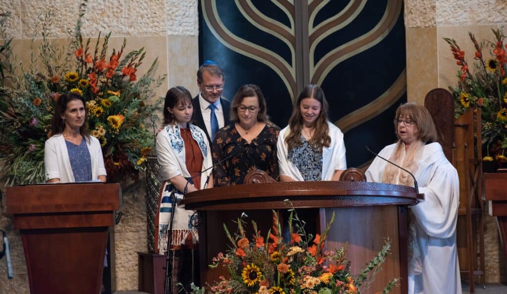 A group of people stand on the bimah, preparing to take their turn reading from the Torah.