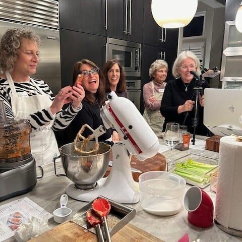 A group of laugh while cooking together in a kitchen.