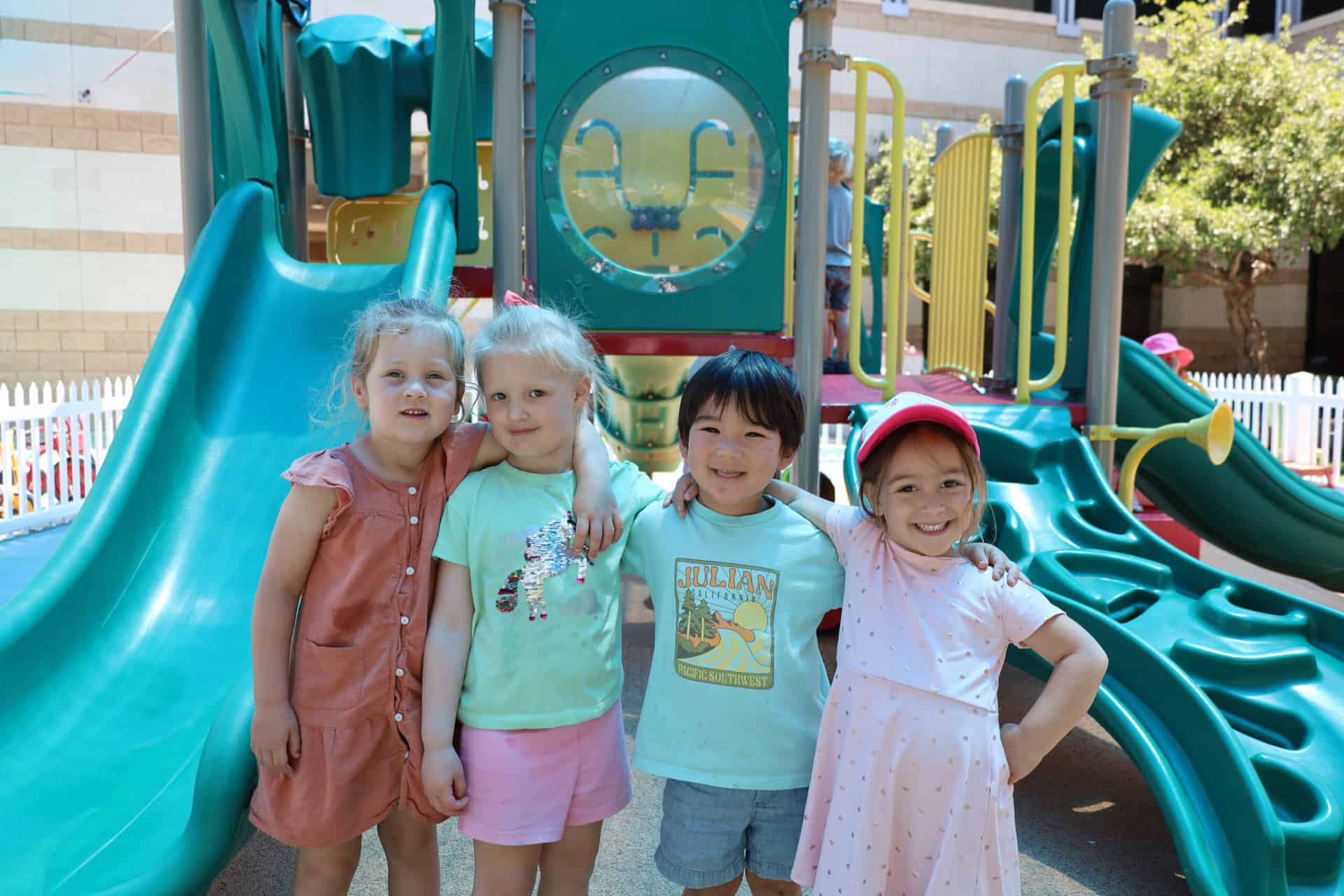 Preschool students pose together on a playground.