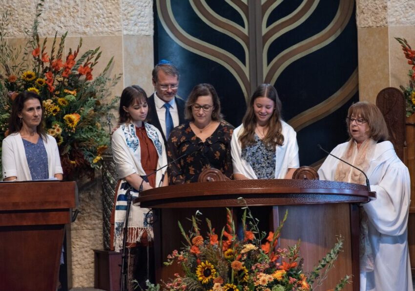 A group of people stand on the bimah, preparing to take their turn reading from the Torah.