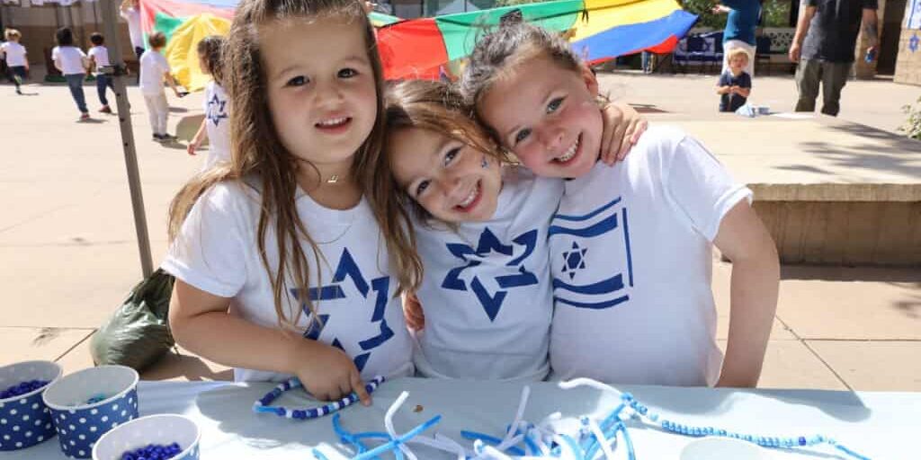 Three young girls pose together at an Israel event