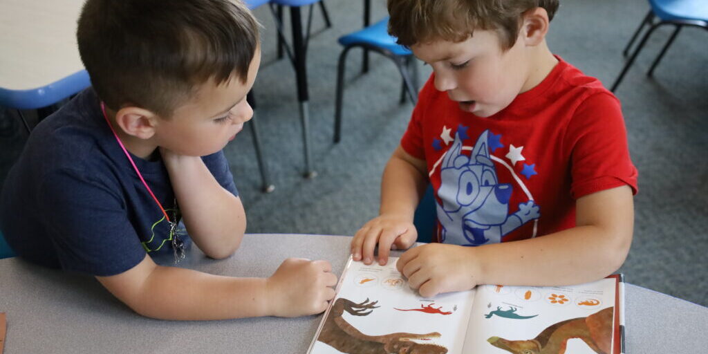 Two children look at a book inside of a classroom at the Bill & Sid Rubin Preschool