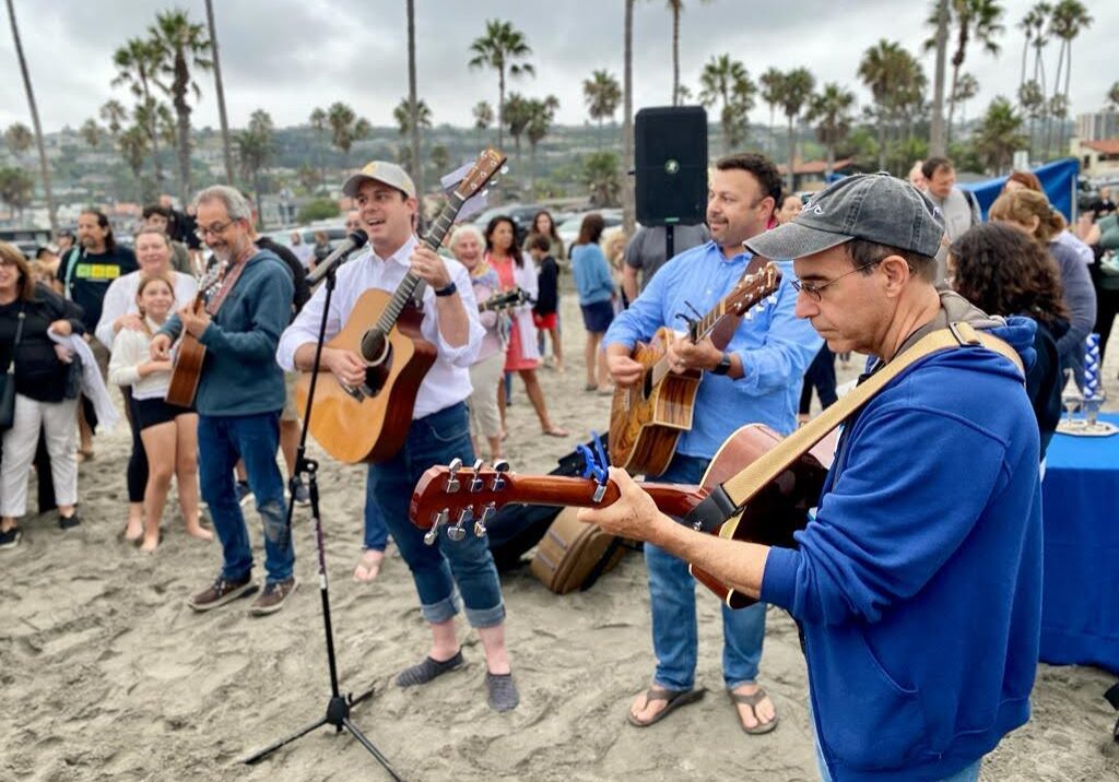 A group of people play guitar on the beach